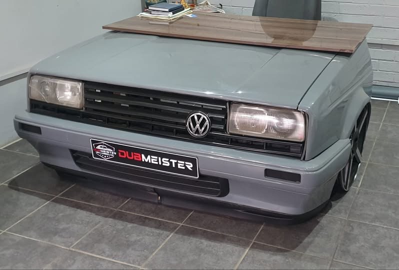 A custom office desk built from the front end of a classic VW, with a Dubmeister plate on the bumper